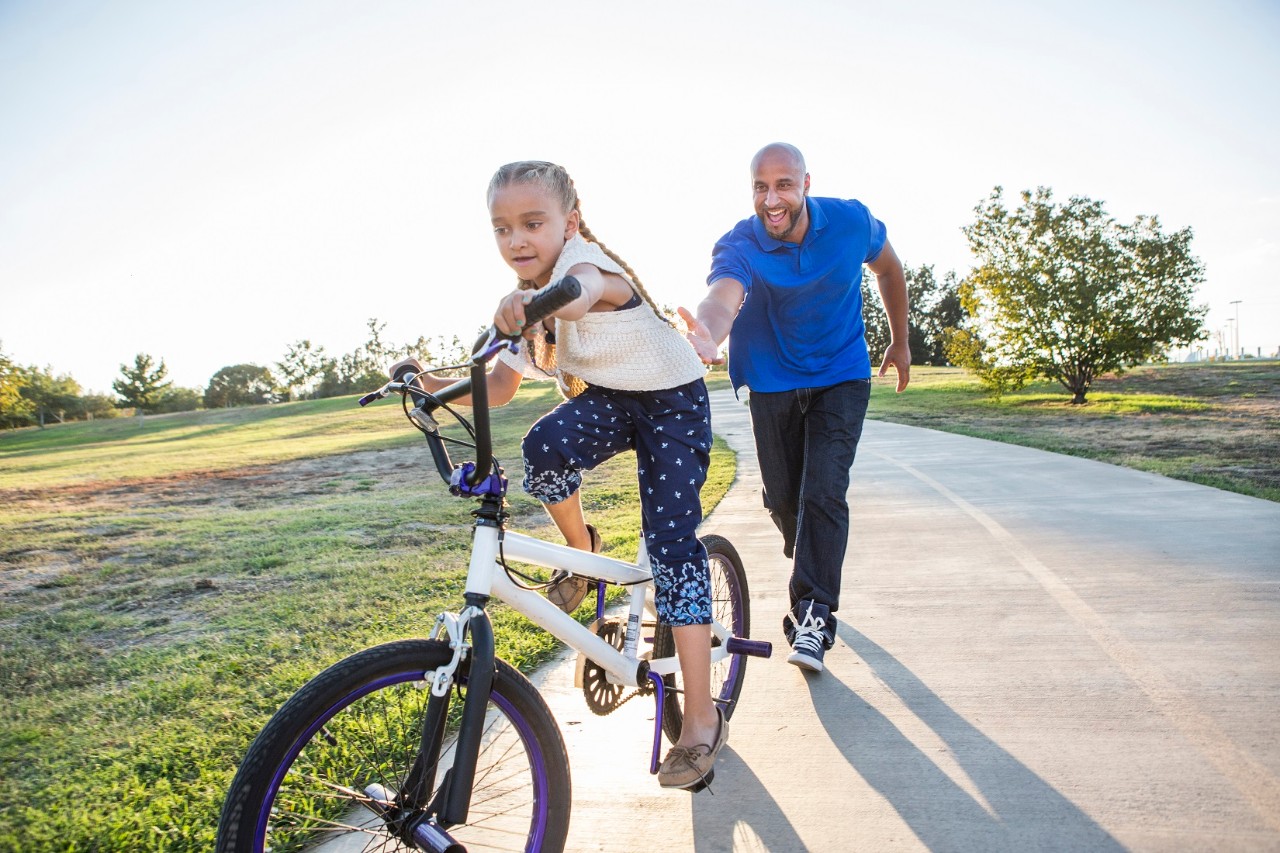 Father helping daughter on bicycle