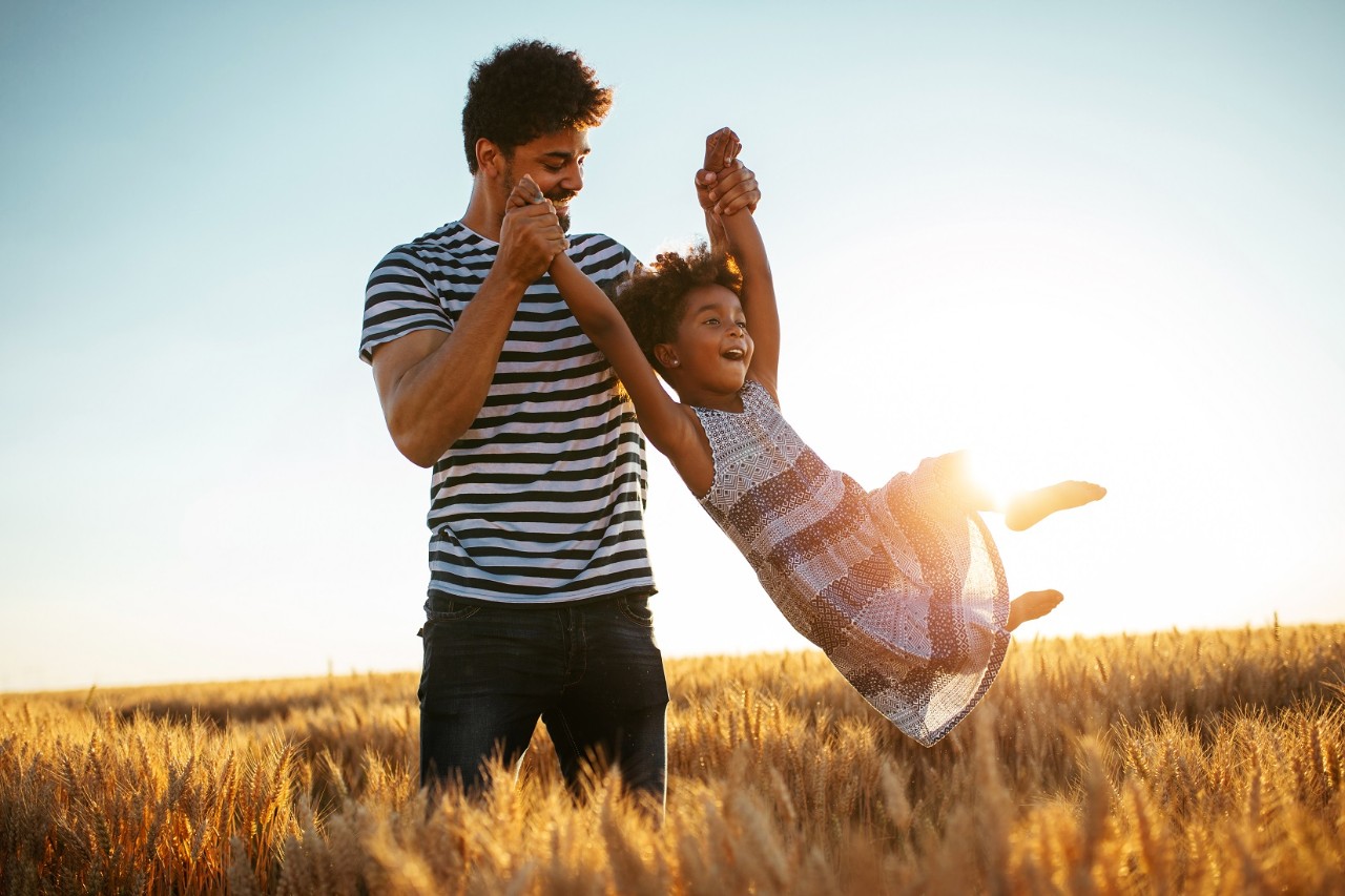 Father swinging daughter in field