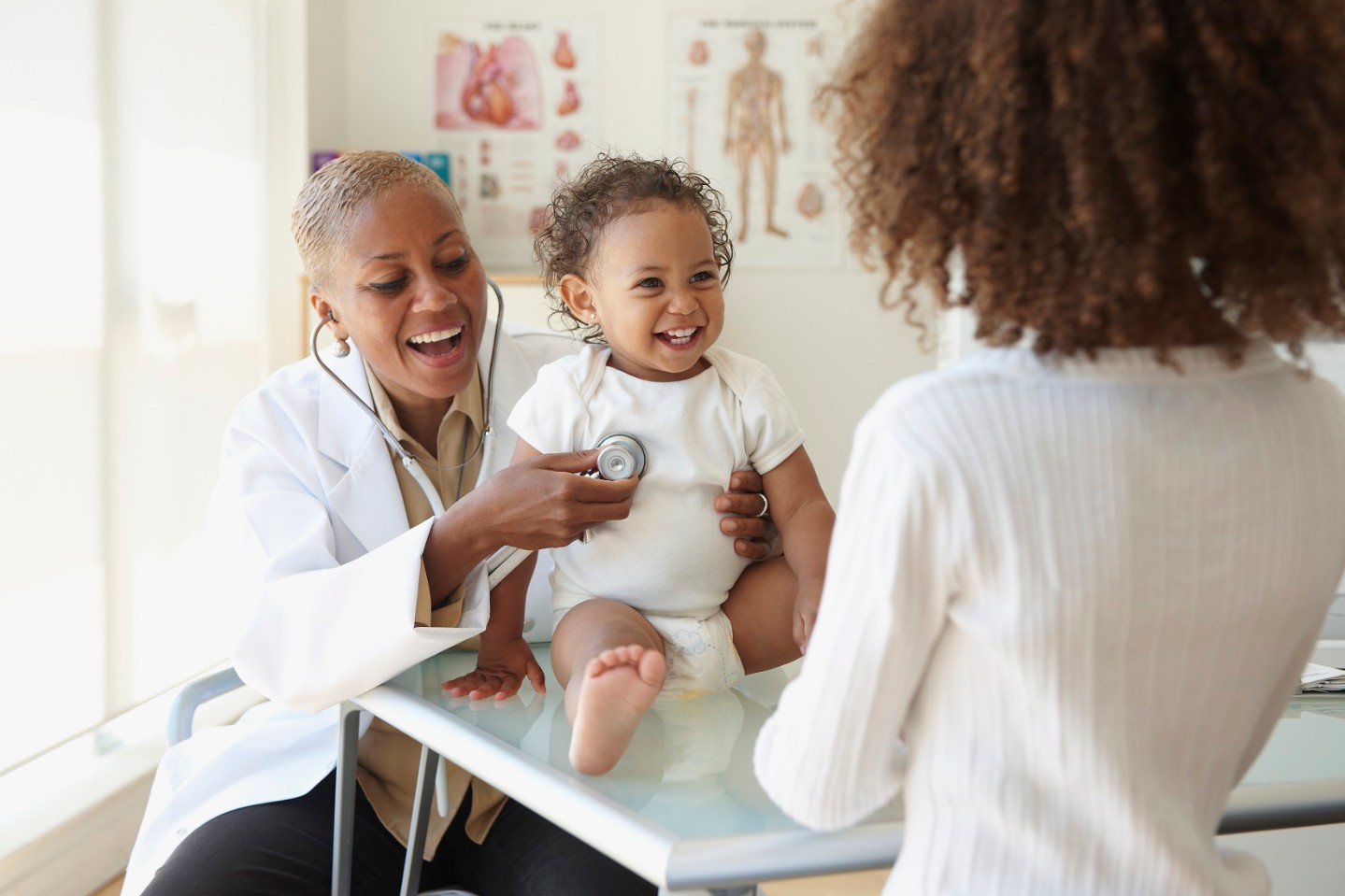 Provider examining baby with mom watching